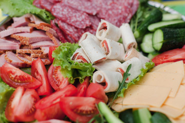 Food for party or picnic. Close up. Sliced vegetables, cheese, tomatoes, salami, bacon, ham, salad, rolls with red fish. Homemade cutting and meal.