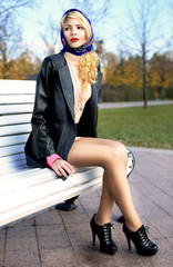 young woman sitting on a bench in autumn park