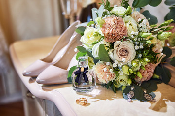 bridal accessories such as shoes, bouquet , ring and perfume lie on a table
