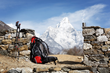 A backpack, hiking poles and a mug with steam on the background of Mount Ama Dablam. The mountain...