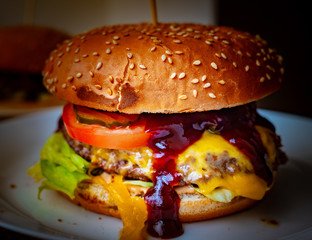 Close-up of delicious fresh home made burger with lettuce, cheese, onion and tomato