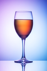 On the table is a glass of wine on a colored background