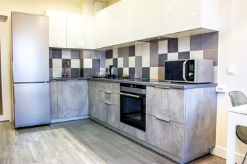 Fototapeta premium Modern home interior kitchen decor elements with gray cement set and segments of luxury furnishings empty apartment with appliances and fridge