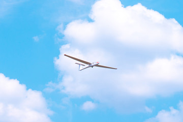 Obraz premium Small glider flying against the blue sky and clouds