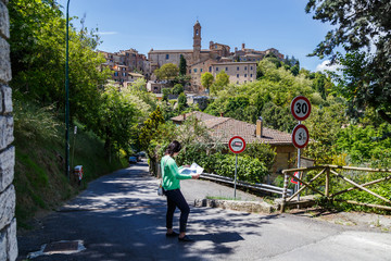 Obraz premium A tourist, young woman, studying the map of Montepulciano, a medieval hills town in the province of Sienna in Tuscany, before entering the historical town. Italy.