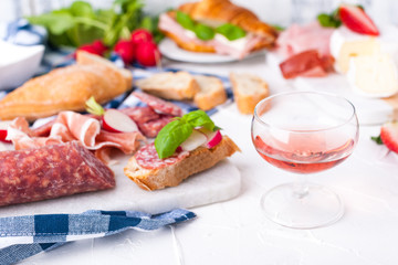 Appetizers table with italian antipasti snacks and wine in glasses. Salami and bruschetta with fresh vegetables on a white background. Free space for text. Traditional snacks for wine.