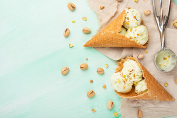 Pistachio ice cream with pistachio nuts and a spoon for ice cream on a light mint background. Top view, Flat lay. Summer mood