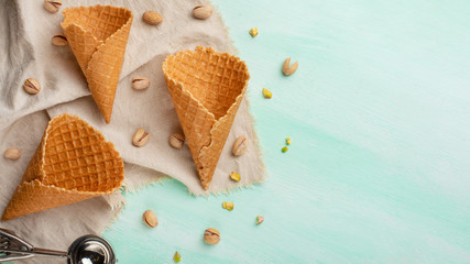 Waffles horns with ice cream on a mint background with a spoon for ice cream and pistachio nuts....
