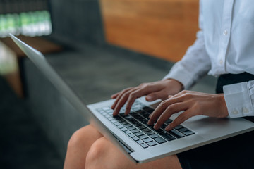Fototapeta na wymiar Woman hands typing laptop keyboard on her lap at the office- woman office worker and businesswomen concept