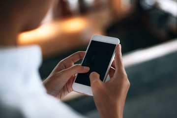 Woman using a smartphone read and text messages with blank space screen display from behind view- woman office worker- digital and communication concept