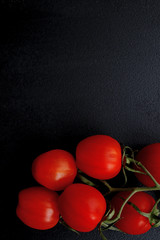 Red cherry tomatoes on black background