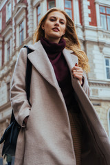 Attractive young blonde woman in casual clothes looking at the camera while walking on the city...