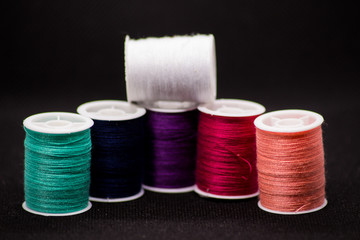 Colourful thread spools on a black background