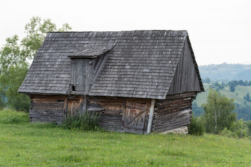 Old wooden barn in field with mountains in background