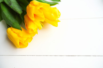 Yellow tulip bouquet on the white wooden background.