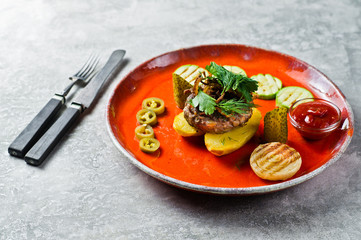 Beef steak with grilled vegetables, zucchini, onion, bell pepper. Gray background, side view