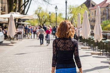 Young woman is walking in on the street in Ljubljana old town,  where all the bars and restaurants are near Ljubljanica river in Ljubljana, Slovenia
