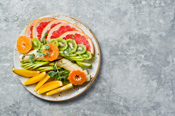 Fruit plate, grapefruit, tangerine, kiwi, orange, banana, Apple. Gray background, top view, space for text