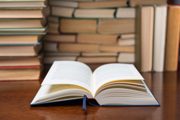 open book on the table, on the background of many books