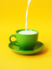 Milk pours in a green cup. The concept of healthy eating, diet drink