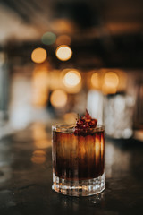 A close up shot of classic Old Fashioned cocktail served with a cube of ice and garnished with cranberries. Concept of bourbon whisky, spirits and alcohol.