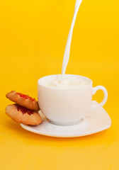 milk pours into a cup, on a saucer a cookies