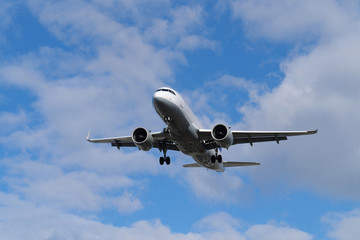 Fototapeta na wymiar Passagierflugzeug in der Luft im Landeanflug und blauer Himmel mit weißen Wolken - Stockfoto