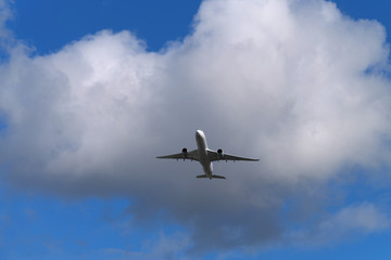 Fototapeta na wymiar Flugzeug in der Luft unter den Wolken und blauer Himmel - Stockfoto