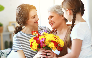 Fototapeta na wymiar mother's day! three generations of family mother, grandmother and daughter congratulate on the holiday, give flowers .