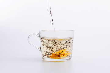 Tea pouring into glass cup isolated on white