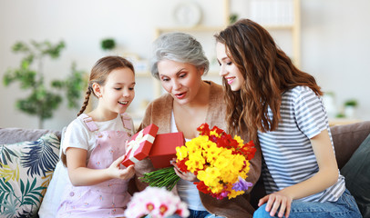Obraz na płótnie Canvas mother's day! three generations of family mother, grandmother and daughter congratulate on the holiday, give flowers .