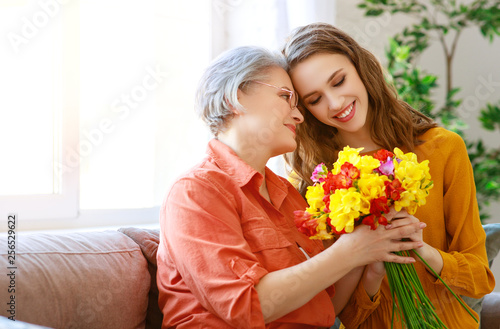 Happy mother's day! adult daughter gives flowers and congratulates an elderly mother on holiday