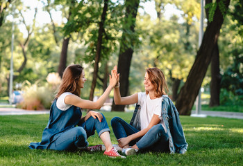Happy female friends raising hands up giving high five in city park