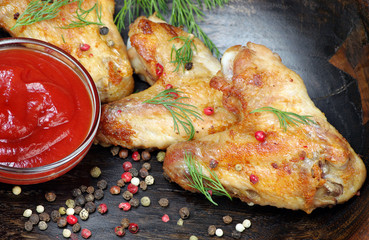 Chicken baked wings on wooden background. chicken wings, ketchup and pepper mix, close-up