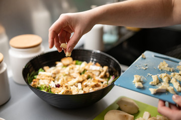 Woman prepares a salad with chicken.