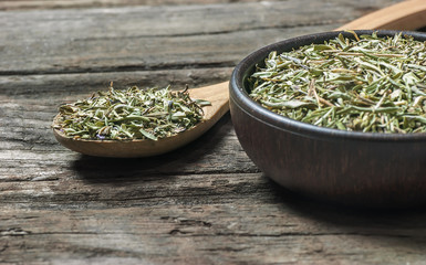 Heap of dry thyme in wooden spoon and in bowl on wooden background. Dried spice zahter thyme and oil concept