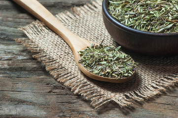 Heap of dry thyme in wooden spoon and in bowl on wooden background. Dried spice zahter thyme and oil concept