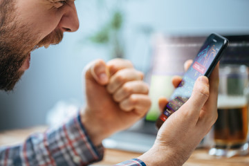 Obraz premium Man celebrating victory after making bets at bookmaker website