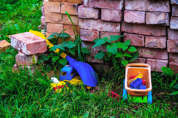 Bricks are stacked on green grass next to children's toys.