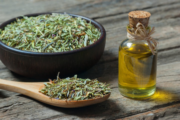 thyme essential oil and Heap of dry thyme in wooden spoon and in bowl on wooden background. Dried spice zahter thyme and oil concept