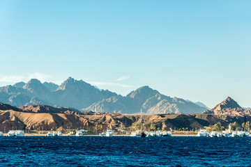 Seascape, view of the blue sea with high bald mountains in the background