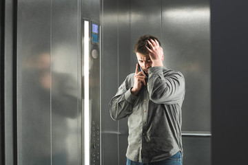 Office worker with claustophobia in the elevator. Man speaks by telephone in the elevator and...