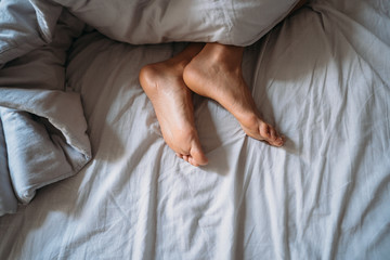 Close-up woman feet alone in white bed