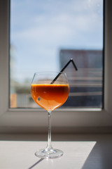 Glass of orange juice over window background.