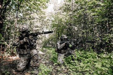 Armed soldiers in camouflage with sniper gun masked in the woods