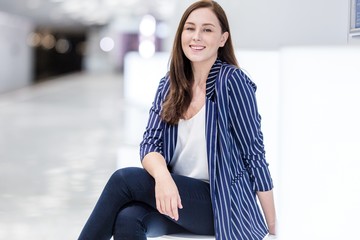 Happy woman on subway platform sitting on bench waiting for train