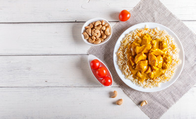 Rice with chicken curry sauce with cashew on white wooden background.