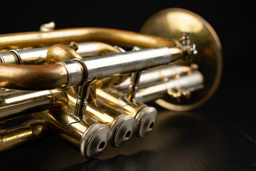 Naklejka premium Old coated patina trumpet on a dark table. An inedible musical instrument.