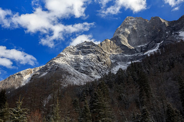 Fototapeta premium ShuangQiao Valley Scenic Area, Siguniangshan - Four Girls Mountain National Park in Sichuan Province, China. Snow Capped Jagged Mountains with clouds forming at the summit. Blue Sky, Snow Mountains