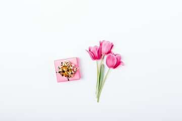 Small pink gift box with golden bow and bouquet of tulip